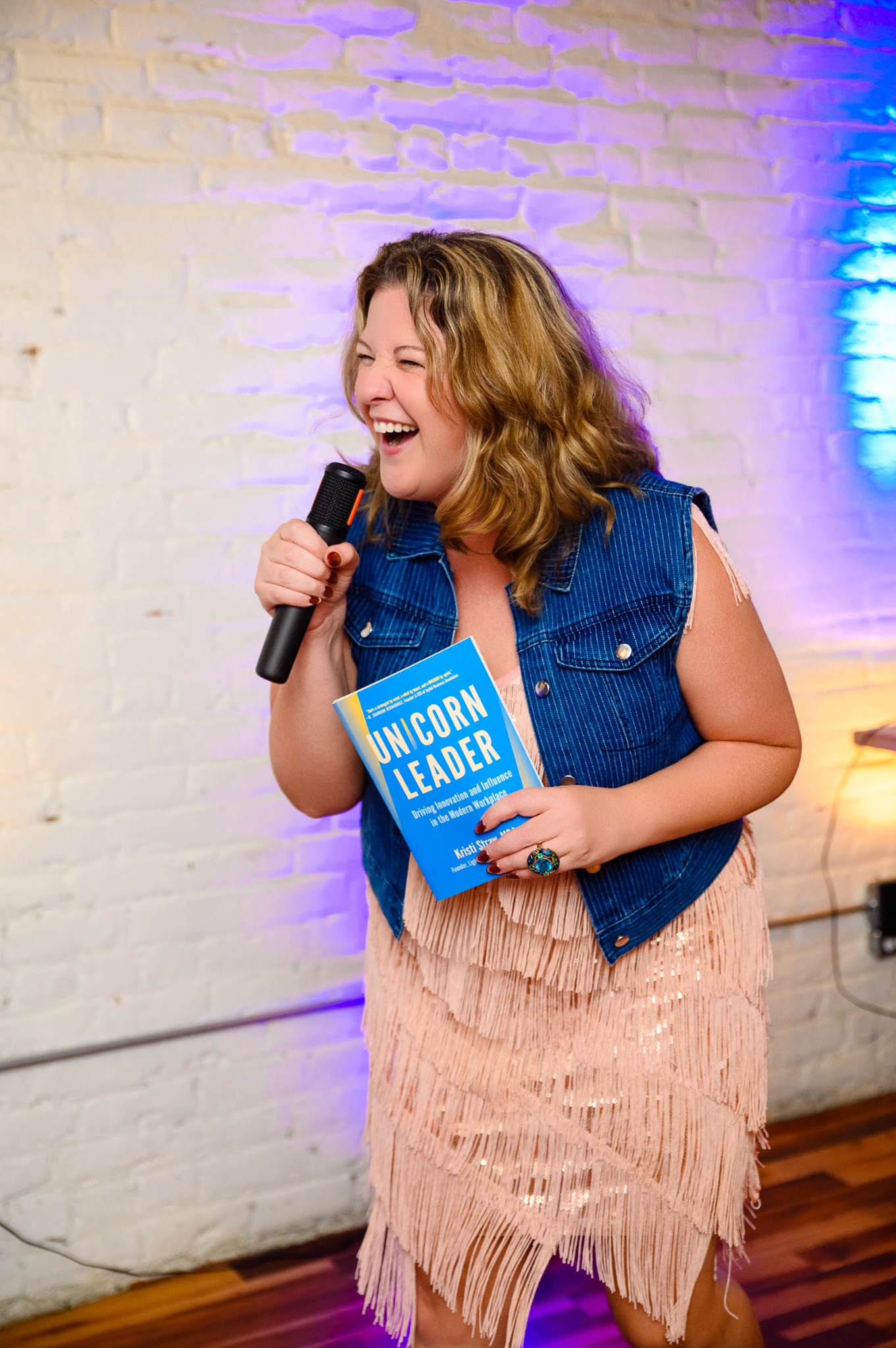 Kristi Straw leading a live conversation while holding UNICORN Leader